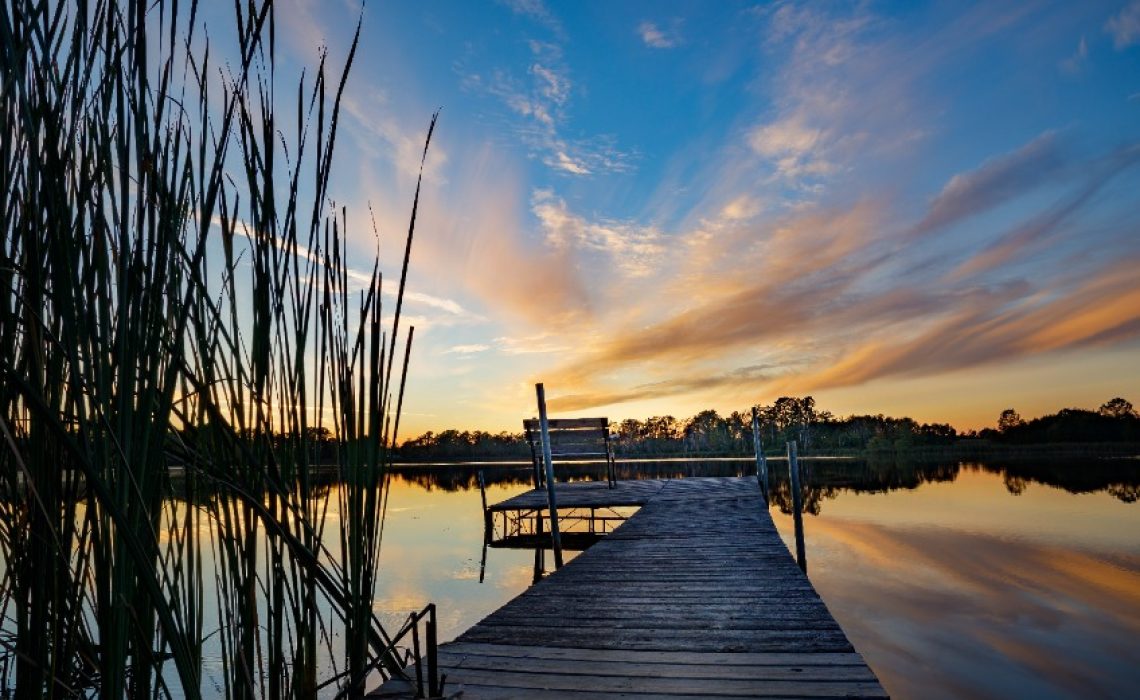 Beautiful sunset reflecting on the water at the public boat landing and dock with bench on Little Moon Lake, Barron County WI